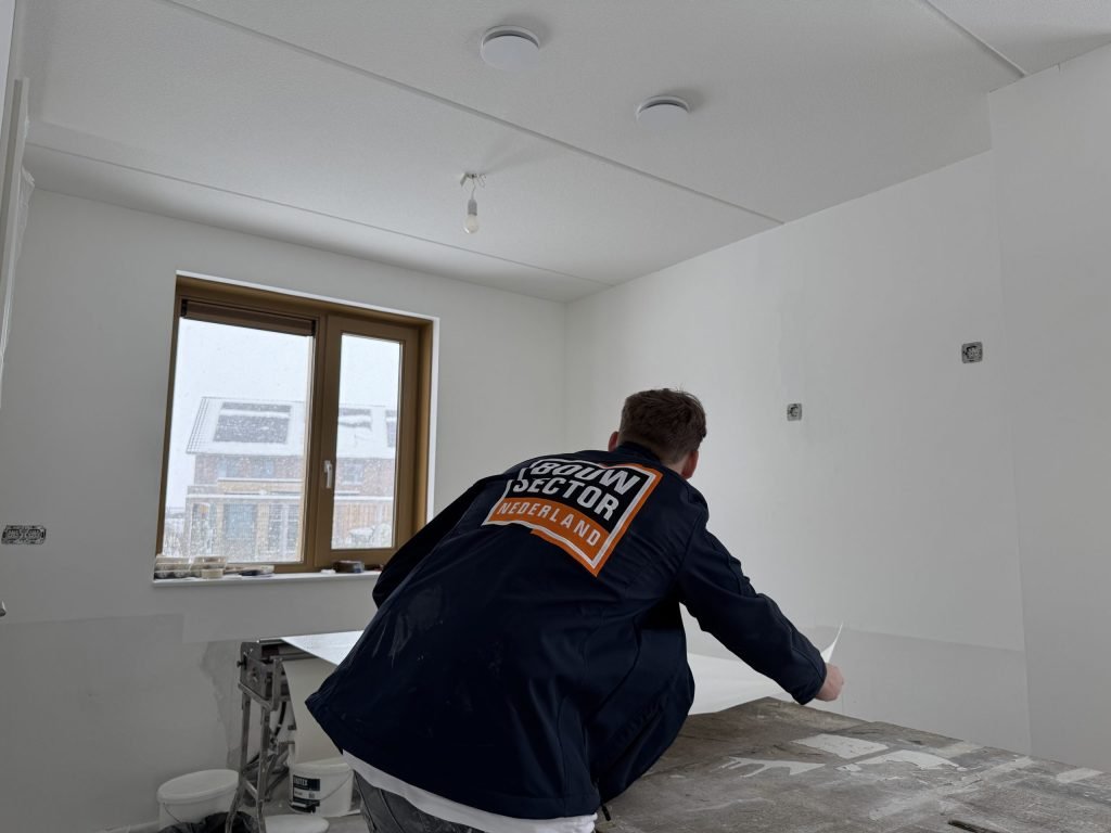 Vakman van Bouwsector Nederland aan de plaktafel in een kale kamer met een raam